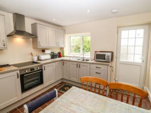 a kitchen with white cabinets and a table with chairs at Idan House in Llanfairpwllgwyngyll
