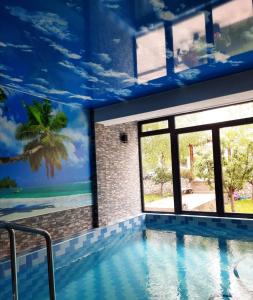 a swimming pool with a palm tree mural on the ceiling at Vila Čair DOPLATA ZA BAZEN in Soko Banja