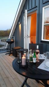 a table on a deck with a candle and bottles at Guldkustens Gästhus - Österlen, Kivik in Kivik