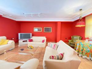 a living room with red walls and white furniture at Casa Pedraza CON PISCINA PRIVADA in Machacón