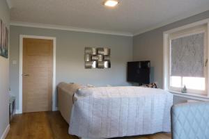 una camera da letto con un letto, una finestra e una televisione di Tanleys B&B a Grantown on Spey