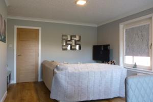 a bedroom with a bed and a window and a television at Tanleys Guesthouse in Grantown on Spey