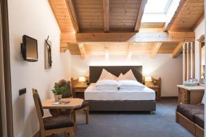 a bedroom with a bed and a table and a couch at Hotel Alpenhof in Tirolo +223 photos