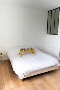 a white bed with a table on top of it at Charmant appartement avec parking privé in Saumur