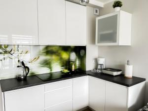 a kitchen with white cabinets and a black counter top at Baltic Comfort Apartment in Kołobrzeg