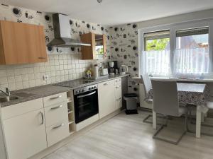 cocina con armarios blancos y fogones en gemütliches, freistehendes Ferienhaus en Koblenz