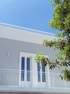 a white house with blue windows and a balcony at Dimora Lilla in Polignano a Mare