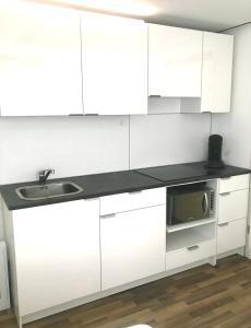 La cuisine est équipée de placards blancs, d'un évier et d'un four micro-ondes. dans l'établissement B@Home Apartments, à Sanem