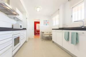 eine Küche mit weißen Schränken und ein Esszimmer in der Unterkunft Apartamento Beach & Chic Cabo Huertas in Alicante