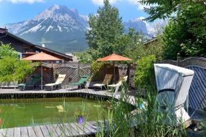 a pool with umbrellas and a mountain in the background at Alpenresidenz Unterrainer in Ellmau