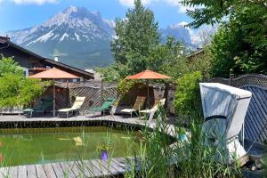 ein Pool mit Sonnenschirmen und ein Berg im Hintergrund in der Unterkunft Alpenresidenz Unterrainer in Ellmau