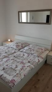 a bed in a white bedroom with a mirror at Appartement Suncano in Crikvenica