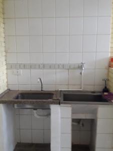 a kitchen with a sink and a tiled wall at O Silêncio que Canta in Águas de Lindóia