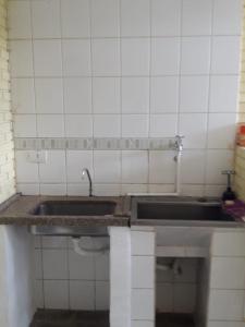 a kitchen with a sink and a tiled wall at O Silêncio que Canta in Águas de Lindoia