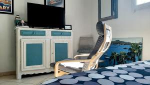 een slaapkamer met een tv en een stoel en een bed bij Les Bains de Mer - station balnéaire Les Sablettes in La Seyne-sur-Mer