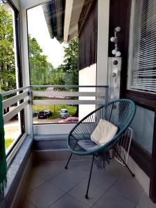 a chair sitting on a porch looking out a window at Art Apartman in Plitvička Jezera