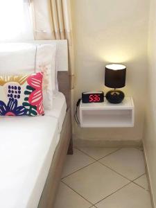 ein Schlafzimmer mit einem Bett mit einer Uhr auf einem Nachttisch in der Unterkunft Reta-Inn Martil Beach in Martil