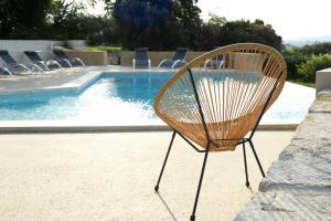 una silla de madera junto a la piscina en La Bergerie de l'etang, en Montels