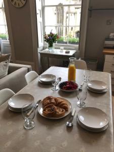 una mesa con un plato de bollería y una botella de zumo de naranja en St Martins Apartment Stamford en Stamford