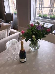 una botella de vino y copas en una mesa con flores en St Martins Apartment Stamford en Stamford