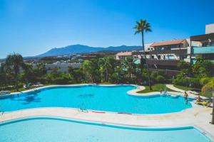 una grande piscina con palme e edifici di Exclusivo apartamento en Los Flamingos Golf a Estepona