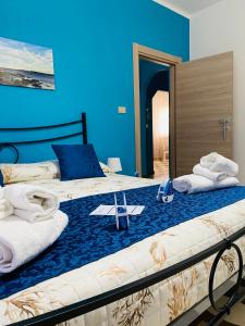 1 dormitorio azul con 2 camas, toallas y zapatos en Villa Del Mare, en Campomarino