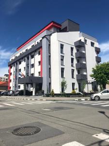 un edificio blanco y rojo con coches estacionados frente a él en Cazare bloc nou ultracentral, en Râmnicu Vâlcea