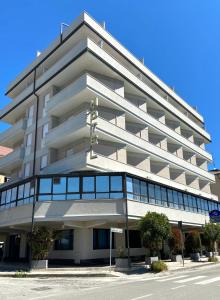 een groot wit gebouw met veel ramen bij Hotel Riviera in Porto San Giorgio