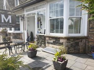 un porche delantero de una casa con mesa y sillas en Montfort Cottage Guest House, en Windermere