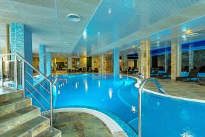 a large swimming pool in a hotel with stairs at Villa Dea & Villa Ina - Villas & SPA Park in Velingrad in Velingrad