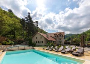 a swimming pool with lounge chairs and a house at Rocker's Inn in Sasca Montană