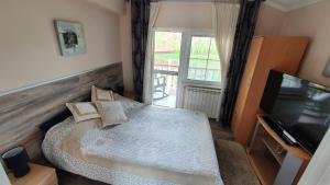 a small bedroom with a bed and a television at Rajski vrt in Vrdnik