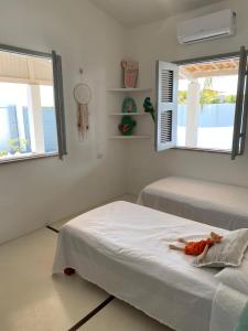 two beds in a room with two windows at Vila Yoga - Kitesurf Pontal de Maceió in Fortim