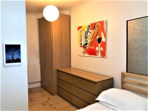 ein Schlafzimmer mit einer Kommode und einem Wandgemälde in der Unterkunft Splendid 1 Bedroom Flat + Terrace (Kentish Town) in London