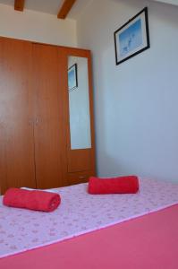 a bedroom with two red pillows on a pink bed at Apartments Brautović in Dubrovnik
