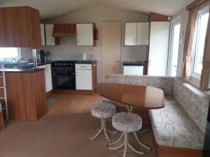 a kitchen and living room with a couch and a table at Beautiful 3-Bedrooms Static Caravan Holiday Home in Clacton-on-Sea