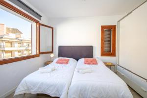 two beds in a small room with a window at Apartments Playa in Alcudia