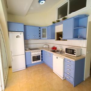 プラヤ・デル・イングレスにあるSamoa Lovely Seaviewのキッチン(青いキャビネット、白い冷蔵庫付)
