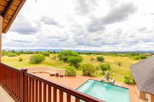 a balcony with a pool and a view of a field at Waterberg House at Zebula - 8 adults and 4 kids in Mabula