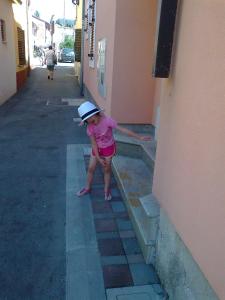 Une petite fille dans un chapeau debout à côté d'un bâtiment dans l'établissement Apartments Edo, à Novigrad