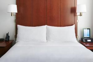 1 cama con almohadas blancas y escritorio con teléfono en Club Quarters Hotel Faneuil Hall, Boston, en Boston