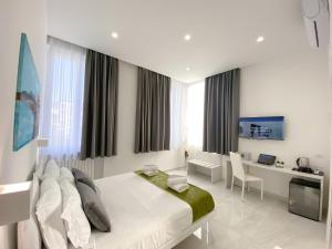 a white bedroom with a bed and a desk and a computer at Villa Gabriella - Rooms & Breakfast in Sant'Agnello