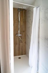 a shower with white curtains in a bathroom at Appartement cosy dans une longère de caractère in Saumur