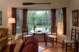 uma sala de estar com um sofá, uma mesa e janelas em The Yellow House on Plott Creek em Waynesville