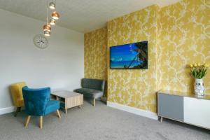 a room with two chairs and a tv on a wall at Palm Court in Skegness