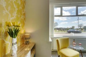 a yellow room with a table and a chair and a window at Palm Court in Skegness +37 photos