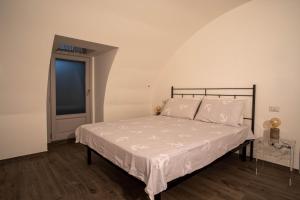 a bedroom with a bed with white sheets and a window at La Dimora del Glicine in Belgirate