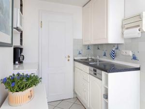 a kitchen with white cabinets and a potted plant at Ferienwohnung Scheunemann in List