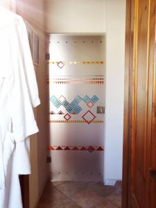 La salle de bains est pourvue d'un mur blanc aux motifs colorés. dans l'établissement B&B CasaCorì, à Orosei