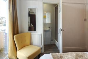 a bedroom with a yellow chair and a bathroom at Palm Court in Skegness